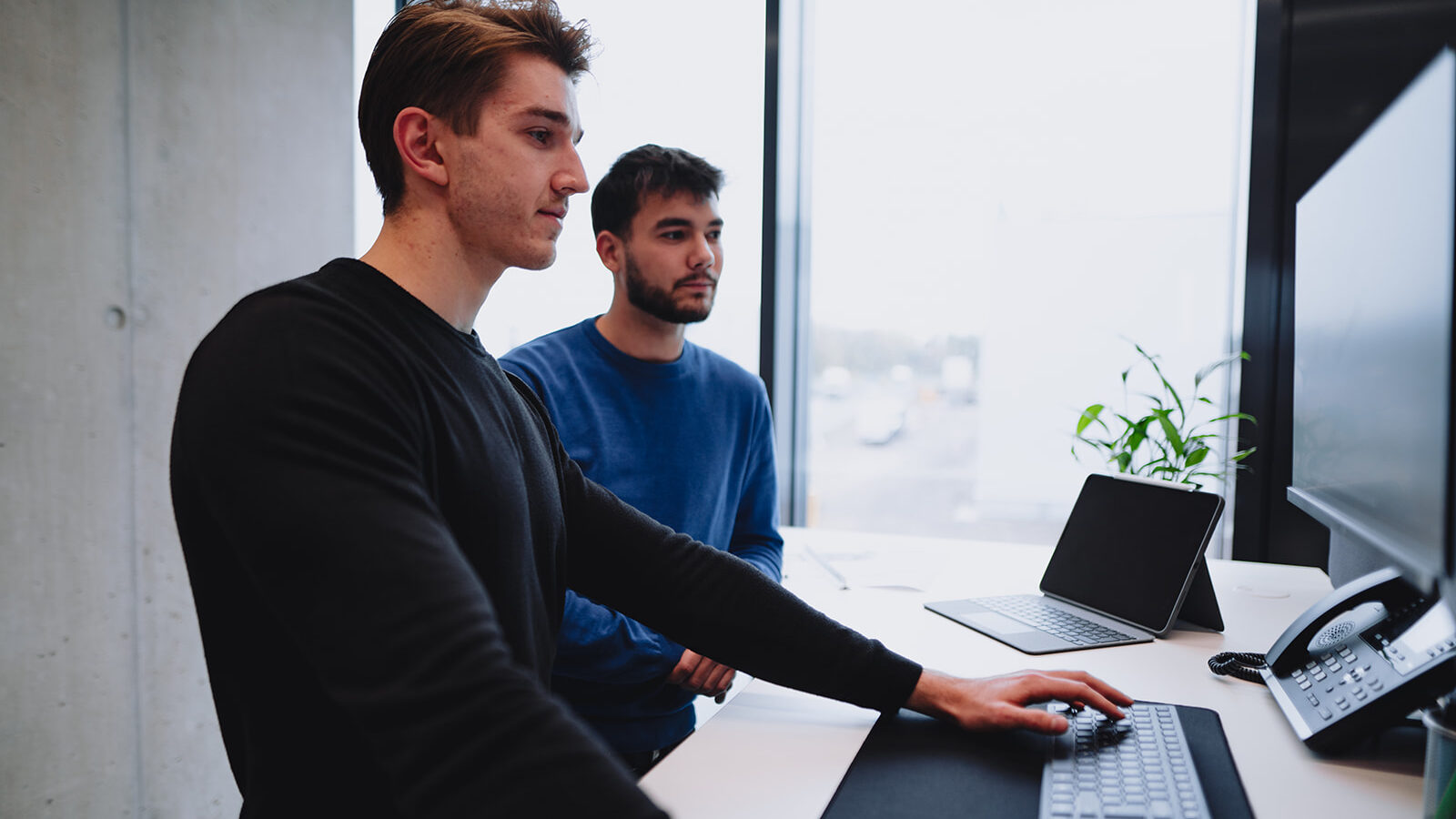 Zwei junge Angestellte von Braun blicken zusammen auf einen Bildschirm.