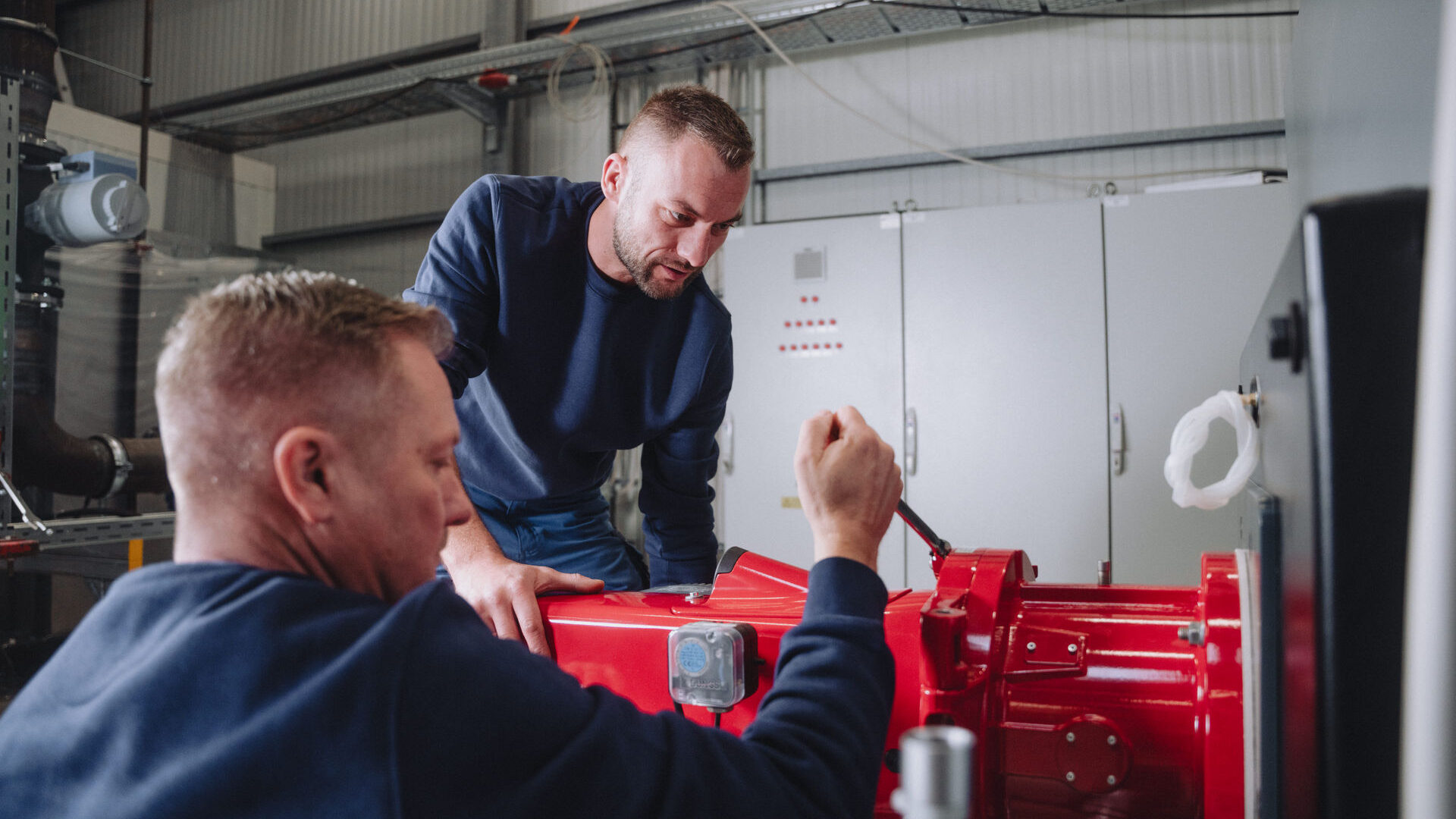 Zwei Mitarbeiter von Braun Liebschützberg bei der Installation einer Pumpe an einem Heizkessel.
