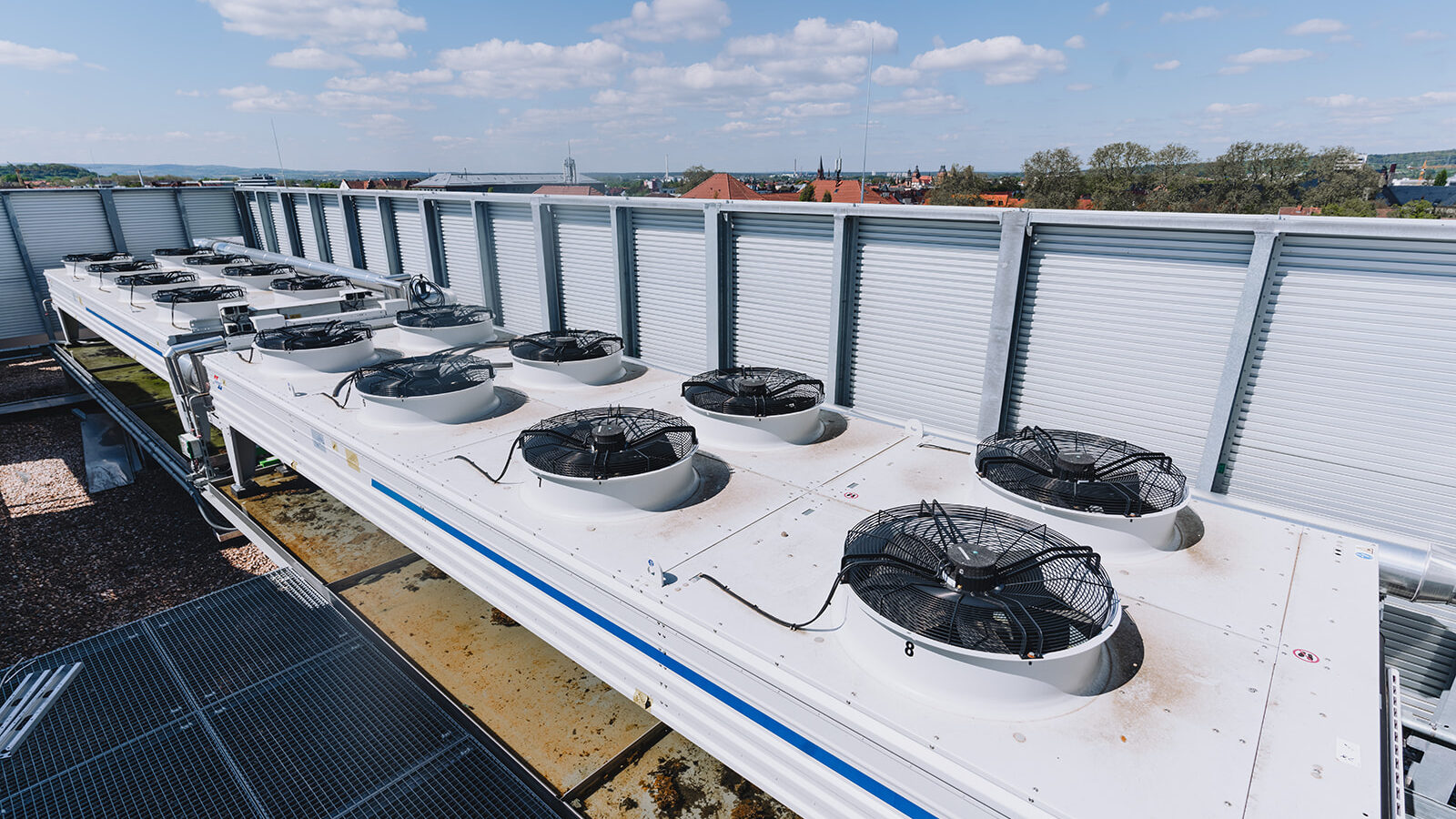 Eine Reihe von Rückkühlern mit Ventilatoren auf einem Hausdach.