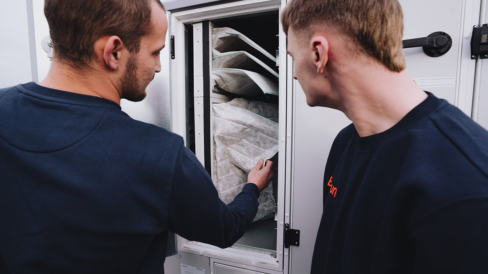 Zwei junge Angestelle von Braun werfen zusammen einen Blick in eine Filteranlage.