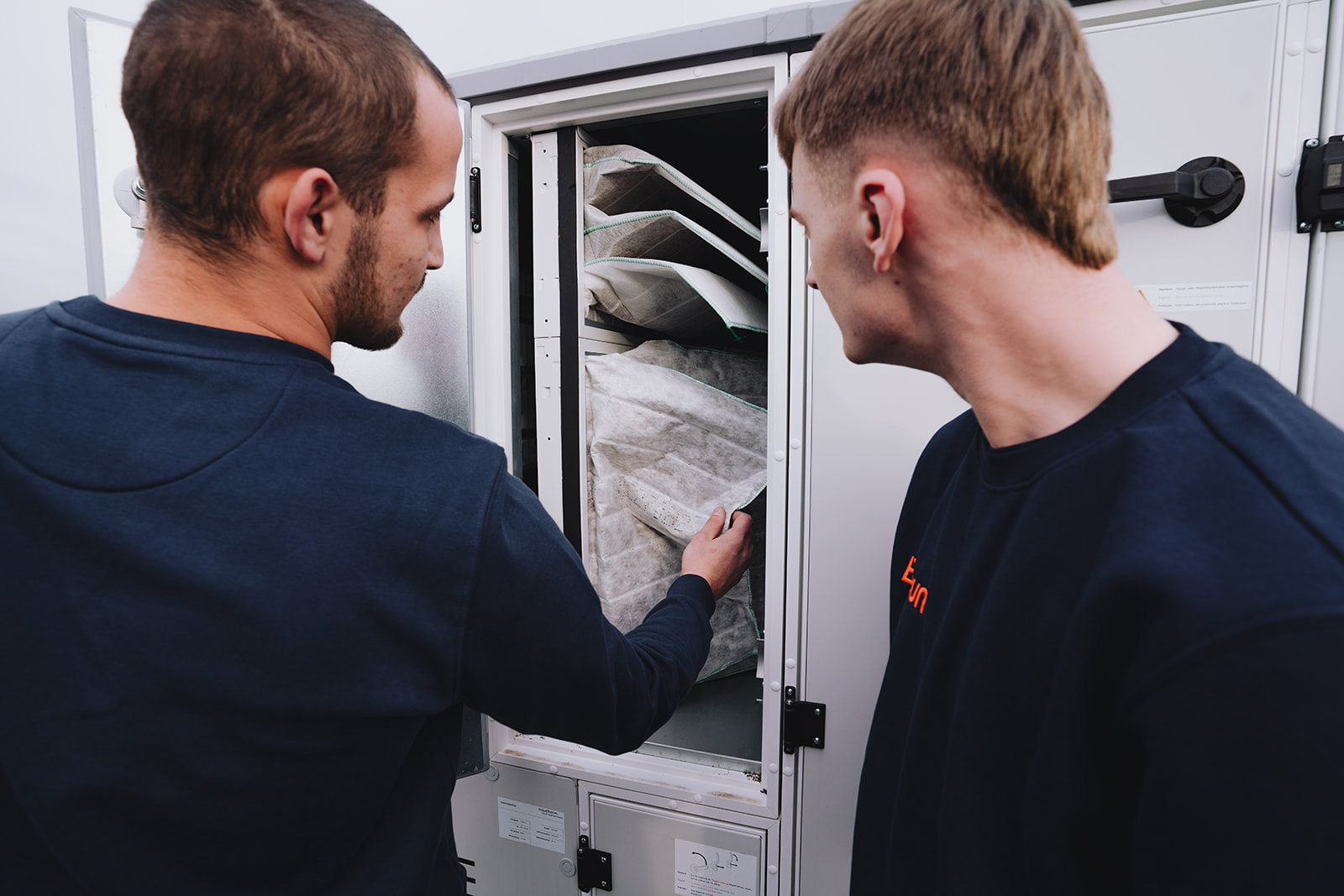Zwei junge Angestelle von Braun werfen zusammen einen Blick in eine Filteranlage.